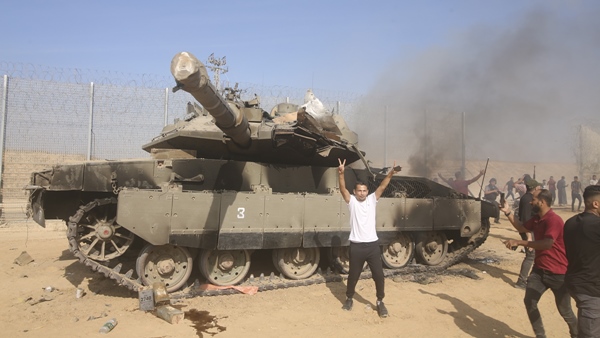 Palestinians celebrate by a burning Israeli tank at the border fence of the Gaza Strip on Saturday, Oct. 7, 2023. The militant Hamas rulers of the Gaza Strip carried out an unprecedented, multi-front attack on Israel. (Photo credit: PTI) Palestinians celebrate by a burning Israeli tank at the border fence of the Gaza Strip on Saturday, Oct. 7, 2023. The militant Hamas rulers of the Gaza Strip carried out an unprecedented, multi-front attack on Israel. (Photo credit: PTI)