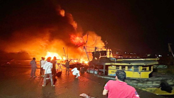 Locals at the site after a fire broke out in a jetty area, in Visakhapatnam, early Monday, Nov. 20, 2023. At least 15 fishing boats were gutted in the fire, according to officials.