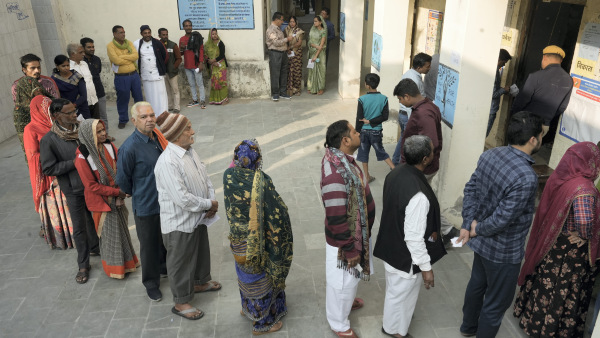 People stand in a queue to cast their votes for the Rajasthan Assembly election, in Pushkar