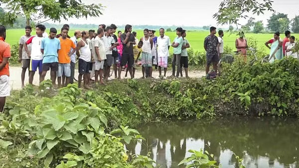 People gather near the pond where prime accused in the alleged rape of a minor girl jumped and died at Dhing in Nagaon district Saturday