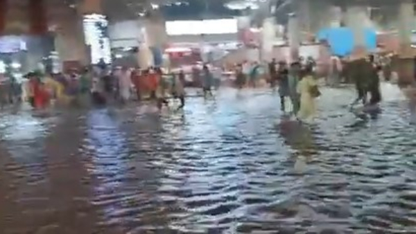 View outside Pune Railway station sees people wading through flooded paths