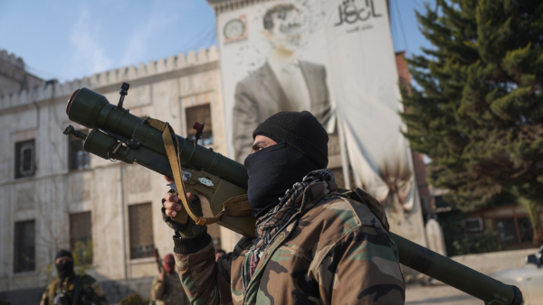 A Syrian opposition fighter holds a rocket launcher in front of the provincial government office where an image of Syrian President Bashar Assad is riddled with bullets on the facade in the aftermath of the opposition s takeover of Hama Syria Friday Dec 6 2024