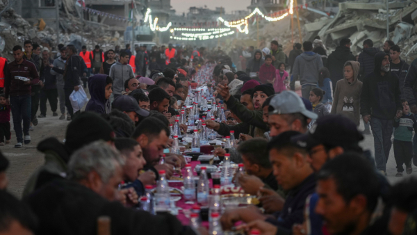 Palestinians sit at a large table surrounded by the rubble of destroyed homes and buildings as they gather for iftar the fast-breaking meal on the first day of Ramadan in Rafah southern Gaza Strip Saturday March 1 2025