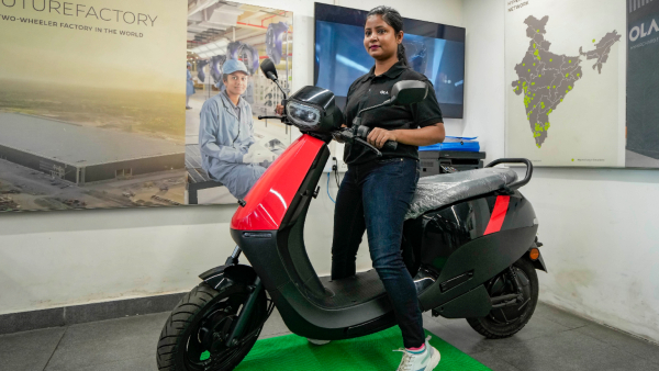 A sales executive poses with Ola S1 X electric scooter