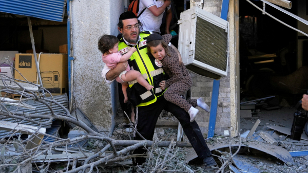 A rescue worker evacuates two children from the site where a missile launched from Iran struck in Haifa Israel Sunday June 22 2025