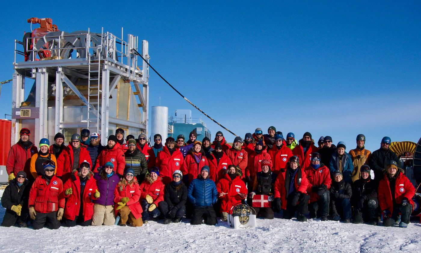 Large team of researchers and engineers in red polar jackets at the South Pole