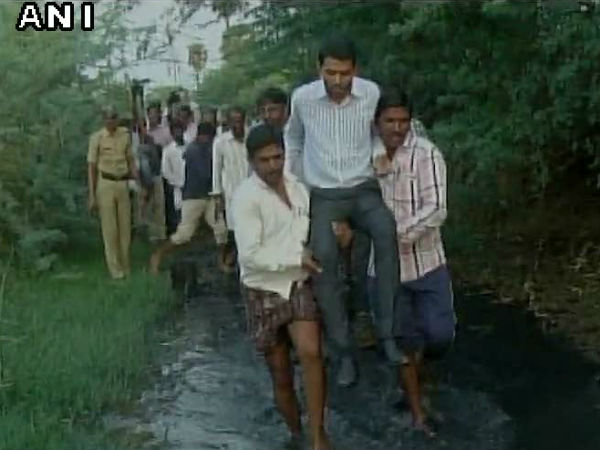 Raichur CEO Zila Panchayat crosses a drain with help of locals Raichur CEO Zila Panchayat crosses a drain with help of locals