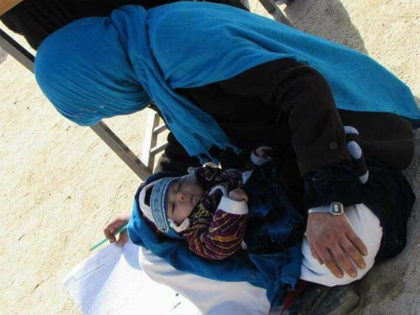 v25 year old Afghan woman takes exam while nursing her baby