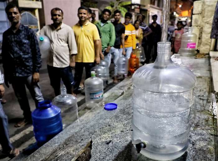 At Jnana Jyothi Nagar in Bengaluru, individuals line up with water cans to obtain drinking water.