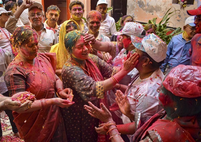 People play with colours on the eve of the festival of Holi