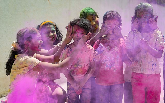 Children play with colours ahead of the festival of Holi