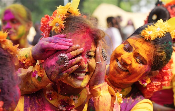Young women apply colour on each other during 'Basant Utsav' celebrations