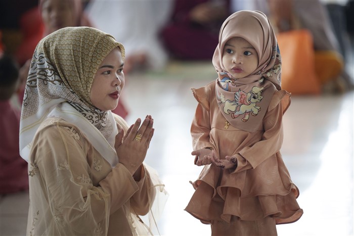A Muslim woman shows her daughter how to pray as they attend prayers at National Mosque for the Eid al-Fitr, marking the end the holy fasting month of Ramadan in Kuala Lumpur, Malaysia,
