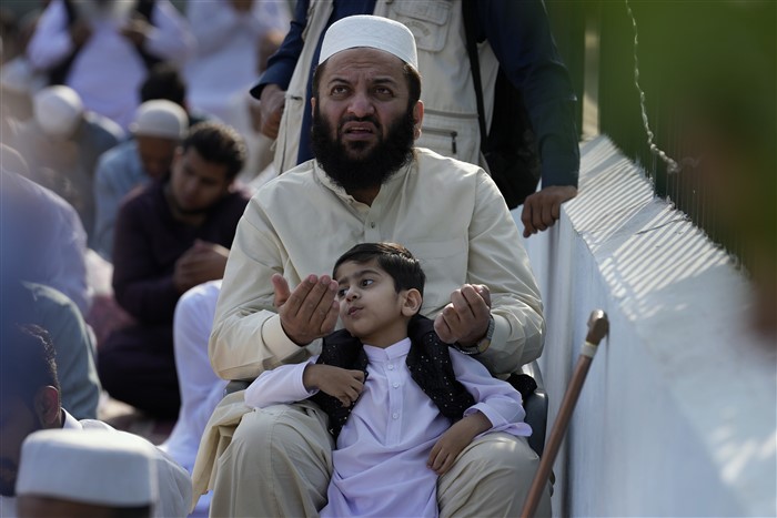 A Muslim with his son attends an Eid al-Fitr prayer, marking the end of the fasting month of Ramadan