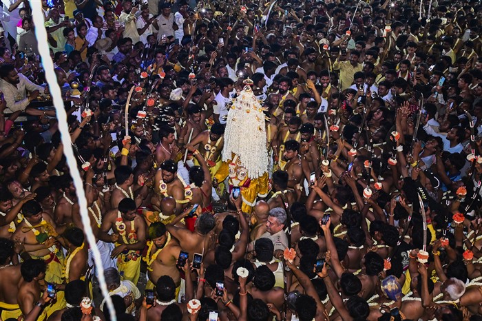 A devotee carries the sacred flower pot 'Karaga' on his head as 'veerakumars' holding swords accompany him during a procession as part of the Karaga festival