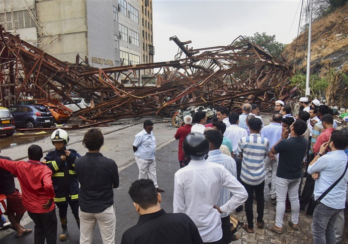Locals gather after an under-construction metal parking tower collapsed on a road due to strong winds and rain