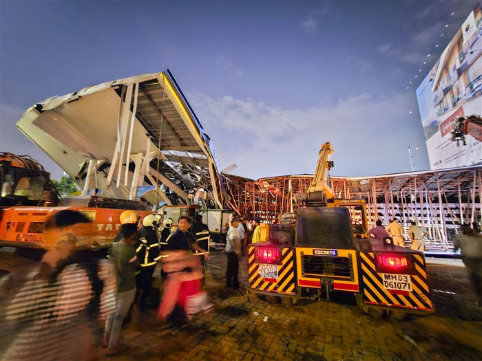 Emergency services personnel at the spot after a huge iron hoarding collapsed on a petrol pump due to strong winds