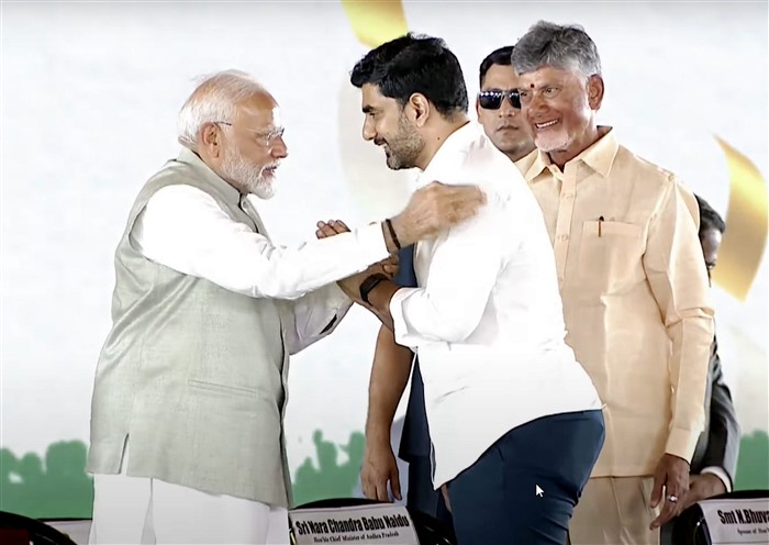 PM Narendra Modi greets Nara Lokesh as Andhra Pradesh CM Nara Chandrababu Naidu looks on during the swearing-in ceremony, in Vijayawada