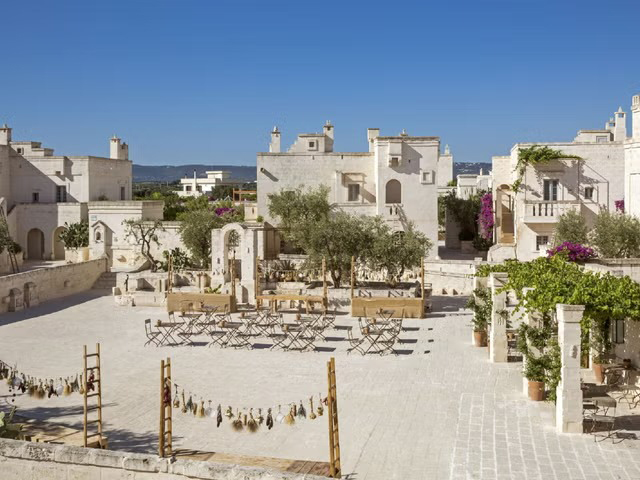 The hotel mimics a traditional Puglian village with whitewashed stone buildings and terracotta roofs surrounding a central piazza.