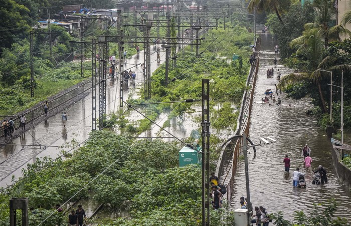 People make their way through a waterlogged street following rains, in Mumbai.