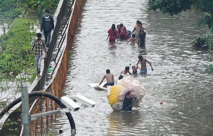 People make their way through a waterlogged street following rains, in Mumbai.