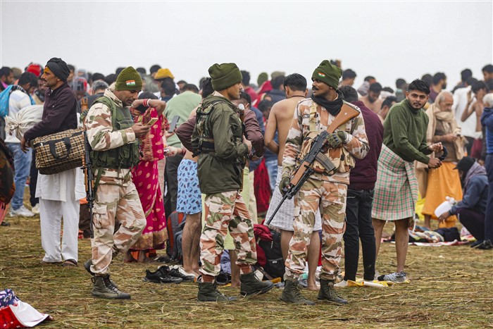 Security personnel stand guard as devotees gather to take a holy dip at the Sangam on the first day of Maha Kumbh Mela 2025, in Prayagraj, Uttar Pradesh, Monday, Jan. 13, 2025.