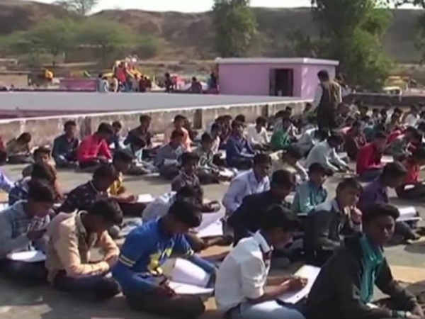 Students write exam on terrace as the dancers perform in school ground 