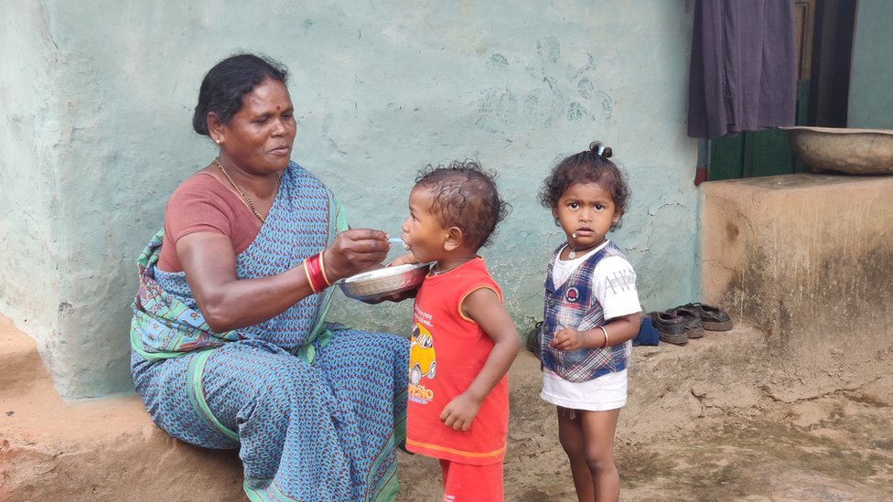 చిన్నారులకు అన్నం తినిపిస్తున్న మహిళ